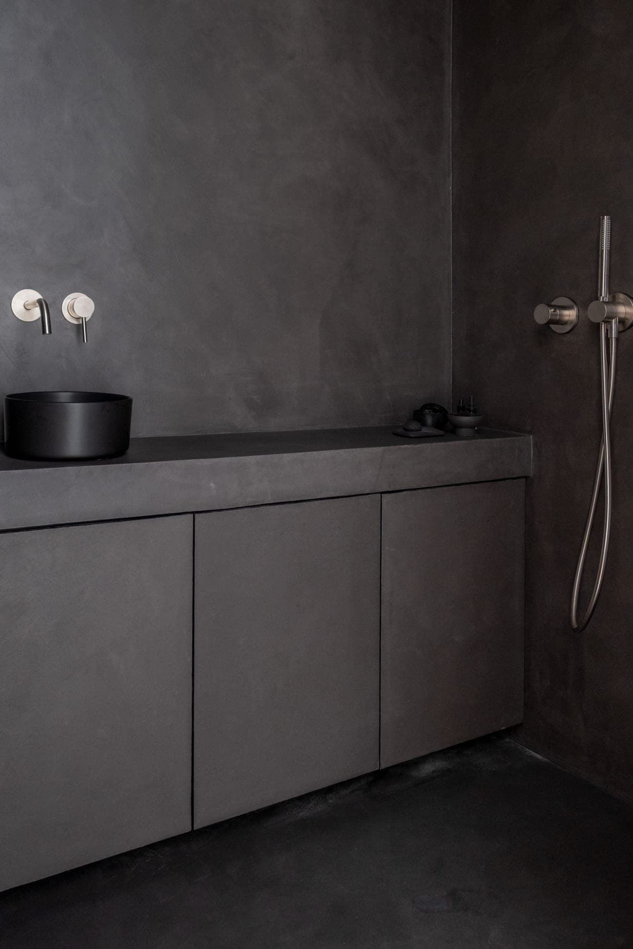 A seamless StucGranito bathroom in a deep, uniform tone — vanity, basin and shower in one continuous stone surface.